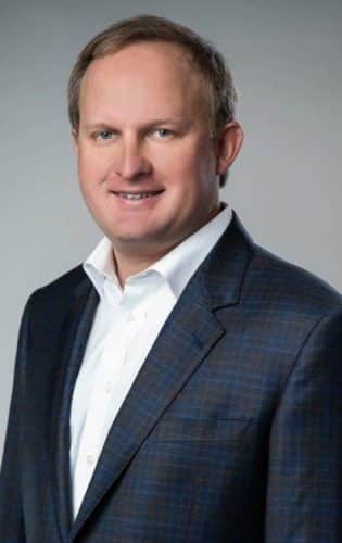 a man wearing a suit and tie smiling at the camera