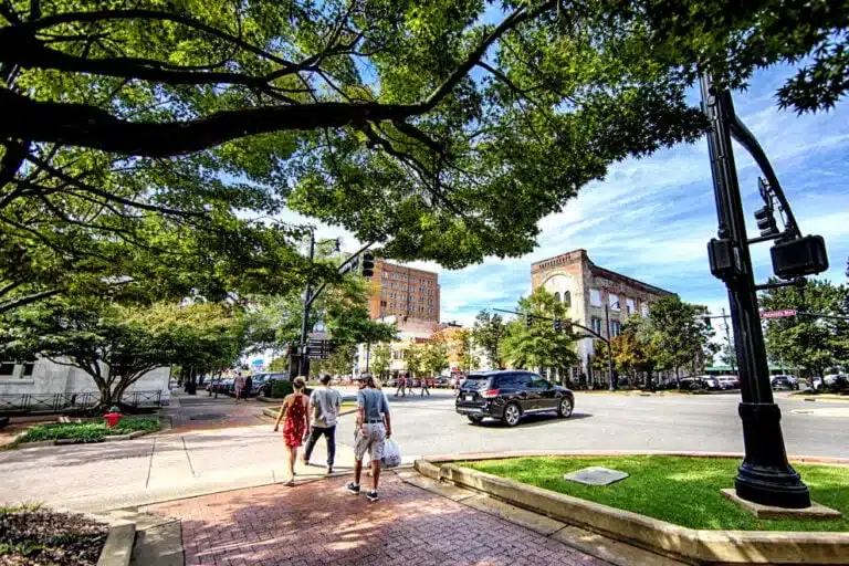 a person walking down a street next to a tree